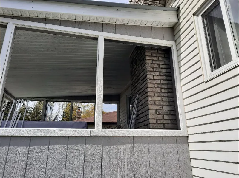 A porch window frame is removed from the exterior wall, exposing the brick chimney beside it.