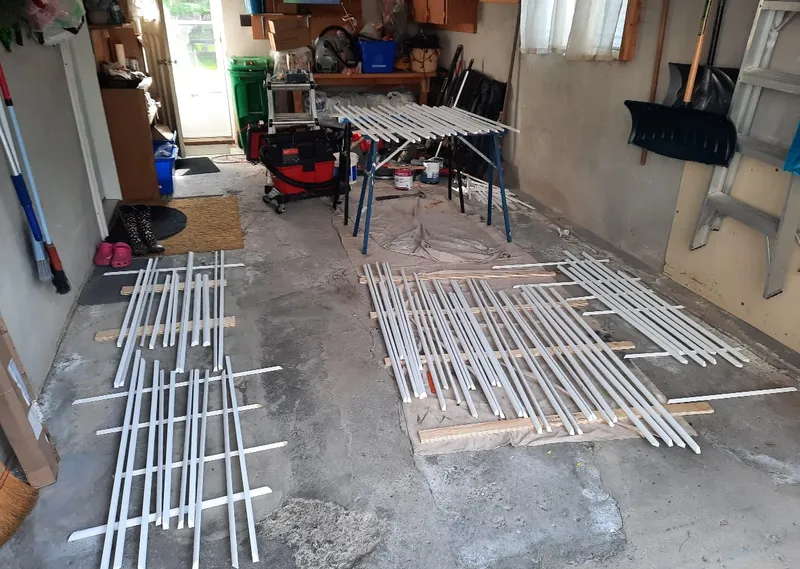 Window sash bars are laid out on a garage floor for reassembly.