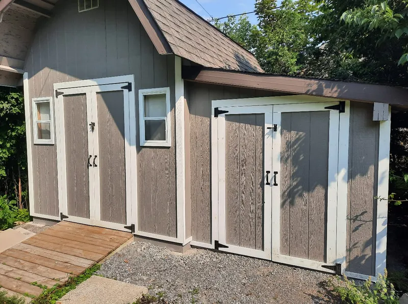 A finished storage shed with board-and-batten siding and two sets of double doors.