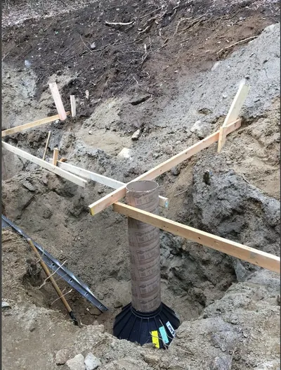 A concrete pier footing sits in a cleared dirt building site.