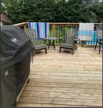 A finished deck furnished with chairs and a grill, ready for use.